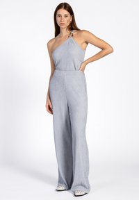 Lichtgrijze, geribbelde jumpsuit met een one-shoulder ontwerp, wijde benen en een decoratieve ringaccent op de schouder.