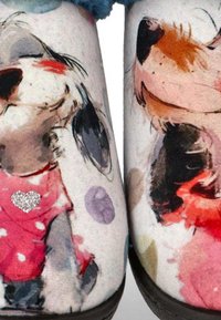 Zapatillas peludas con una parte superior de tela suave que presenta ilustraciones divertidas de perros, un detalle de corazón y patrones de puntos coloridos sobre un fondo claro.