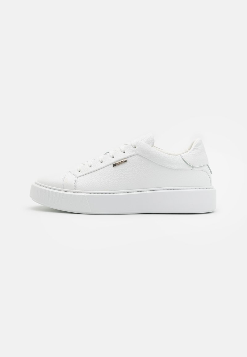 Zapatillas de cuero blancas con superficie texturizada, puntera redonda, suela de goma plana y talón reforzado, con un diseño minimalista y un detalle plateado.