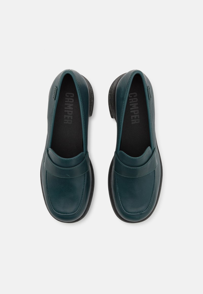 Scarpe slip-on in pelle verde con una finitura liscia, punta rotonda e suola in gomma nera. Presentano una tomaia cucita e accenti minimali.