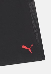 Calções atléticos pretos com um painel lateral texturizado, apresentando um destacado logotipo vermelho da Puma no lado inferior esquerdo.