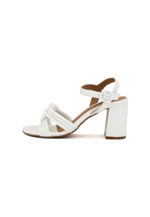 Sandal con tacco alto bianco caratterizzato da cinturini incrociati, punta quadrata, cinturino alla caviglia regolabile e un robusto tacco a blocco. Soletta marrone visibile.