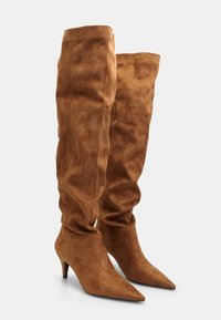 Bruna over-knee stövlar gjorda av mjuk mocka, med spetsig tå och smal klack, samt en slouchig design upptill.