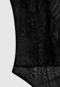 Body nero realizzato in tessuto mesh trasparente con dettagli in pizzo su un lato, caratterizzato da una texture liscia e un design aderente.