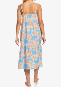 Robe maxi bleu clair avec un motif de feuilles de palmier pêche, bretelles fines ajustables, taille froncée, et un design de jupe à étages.