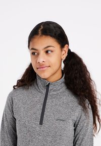 Grijze fleece top met ritssluiting en hoge kraag, van gestructureerde stof, met een klein logo op de borst. Heeft een halve ritssluiting.