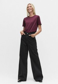 Burgundin värinen crew neck t-paita ja korkeavyötäröiset mustat leveälahkeiset farkut. Farkuissa on hienovarainen täpläinen tekstuuri, molemmilla vaatteilla on rento istuvuus.