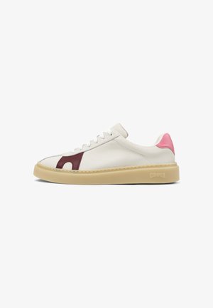 Witte leren sneaker met beige zool, bordeauxrode zijaccent, roze hielriempje en witte veters, met "Camper" op de zool gebrandmerkt.