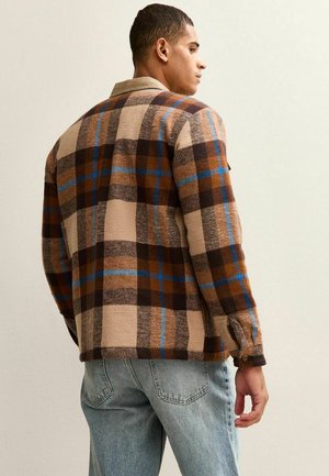 Chaqueta a cuadros marrón y beige con detalles en azul, hecha de un tejido texturizado. Presenta un cuello con solapa y botones en las mangas.