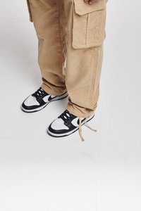 Zwart-witte sneakers met een geperforeerde leren neus, zwarte accenten en tan kleurige veters. Gepaard met beige corduroy cargobroeken.