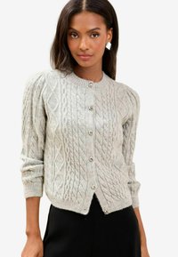 Cardigan de tricot cu model cable în nuanță gri deschis, cu decolteu rotund, mâneci lungi și nasturi decorativi, având un tiv ușor scurtat și un design texturat.