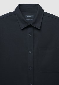Camicia nera button-up realizzata in tessuto testurizzato, con colletto alla francese, taschino frontale e design a vestibilità regolare.