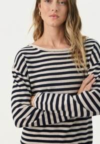 Maglione a righe con scollo ampio e maniche lunghe. Presenta righe orizzontali blu navy e crema, realizzato in un tessuto morbido e texturizzato.