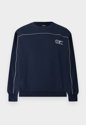 Μπλε σκούρο φούτερ με μακριά μανίκια και λευκές ρίγες κατά μήκος των μανικιών και του στήθους, με μικρό λογότυπο "YT" με σφαίρα στο πάνω αριστερό μέρος του στήθους.