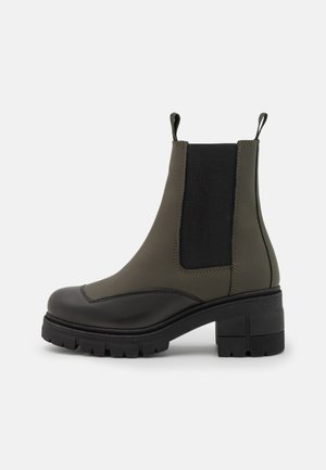 Ankle boots with a sleek olive green leather upper, black elastic side panels, chunky black heel, and patterned sole for traction.