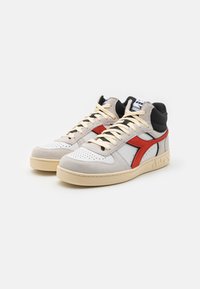 Sneaker alte con tomaia in suede grigio e pelle bianca, dettagli neri, logo rosso, suola crema e lacci beige. Punta forata per ventilazione.