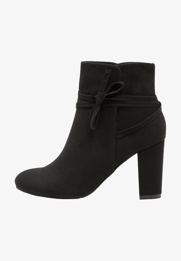 Bottine en daim noir avec talon bloc, bout arrondi et détail décoratif de lien enveloppant sur le côté.