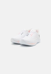 Baskets de sport blanches avec un dessus en tricot texturé, présentant des accents roses et un col rembourré. Design léger avec une semelle flexible.