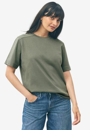Olivegrünes Baumwoll-T-Shirt mit kurzen Ärmeln und rundem Ausschnitt, featuring einen lockeren Schnitt und minimalen Nähdetails an den Schultern.