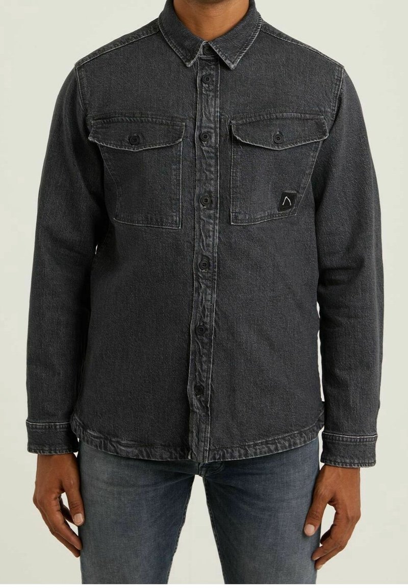 Camicia in denim scuro con colletto a punta, due tasche frontali e chiusura con bottoni. Presenta sbiadimenti leggeri e cuciture a contrasto. Maniche lunghe.