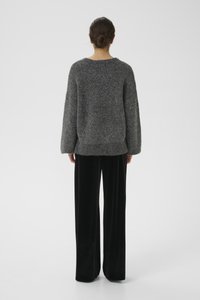 Grijs gebreid trui met lange mouwen en een ronde halslijn, gecombineerd met zwarte wijde broek, textiel met zichtbare vezels.