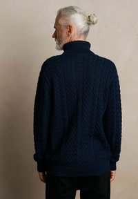 Granatowy sweter z grubej dzianiny z wysokim kołnierzem, z prążkowanymi mankietami i dołem, prezentujący teksturowany wzór na całej powierzchni.