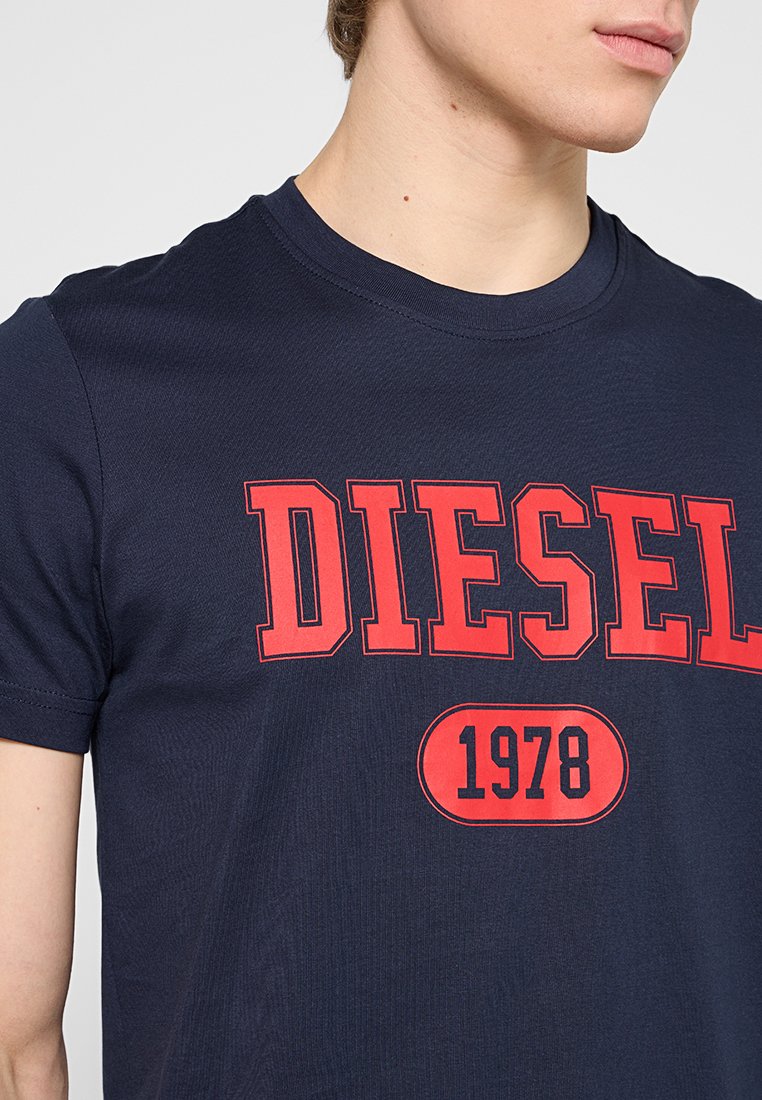 Marineblauwe katoenen T-shirt met een gedurfde rode "DIESEL" logo en het jaar "1978" in een ronde badge eronder. Standaard ronde hals ontwerp.