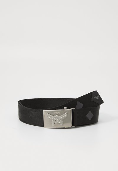 Kangast must vöö, millel on sile tekstuur, ja hõbedane metallist põlk, millel on reljeefne tiivuline logo ja teemantaktsent.