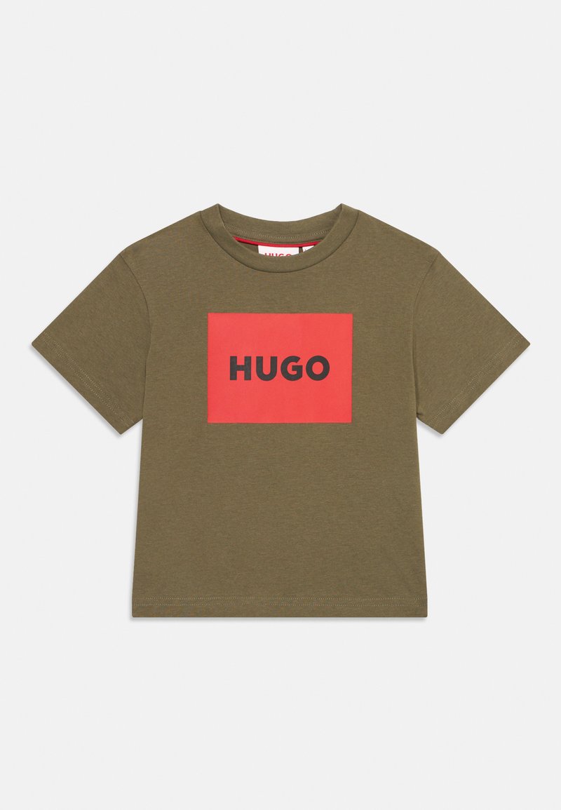 Olivnozeleni bombažni T-shirt s kratkimi rokavi, okroglo ovratnikom in rdečim pravokotnim grafičnim motivom, na katerem je beseda "HUGO" v debelih črnih črkah.
