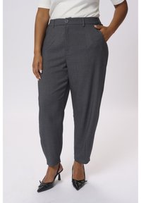 Pantaloni grigi a vita alta con taglio dritto, caratterizzati da una texture sottile e due tasche laterali, abbinati a décolleté nere con punta appuntita.