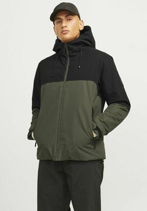 Chaqueta con cremallera en negro y verde oliva, con capucha, presenta dos bolsillos laterales, cordones ajustables y una textura de tela suave.