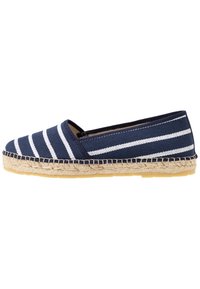 Marinblå canvas-espadrille med vita horisontella ränder, naturlig jutaropesula och texturerad detalj längs kanten. Platt slips-på-design.