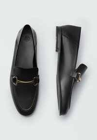 Schwarze Lederloafers mit glatter Textur, ausgestattet mit einer goldfarbenen Schnalle und einem niedrigen Profil. Beinhaltet einen seitlichen Riemen zur Anpassung.