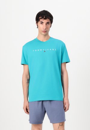 Türkises T-Shirt mit kurzen Ärmeln und Rundhalsausschnitt, mit weißem "TOMMY JEANS"-Schriftzug, aus weichem Baumwollmaterial gefertigt.
