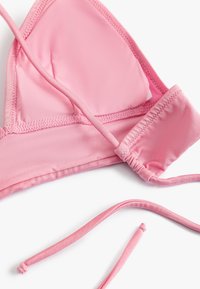 Top de bikini rosa con forma de copa triangular, textura suave, tirantes ajustables y detalles fruncidos en la banda para un mejor ajuste.
