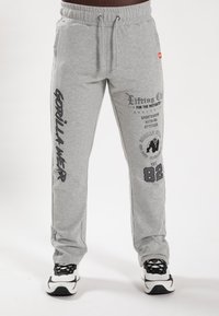 Grijze sweatpants van een katoenmix stof. Voorzien van bedrukte graphics op het linker been en het zakgebied, met een elastische tailleband en een koord.