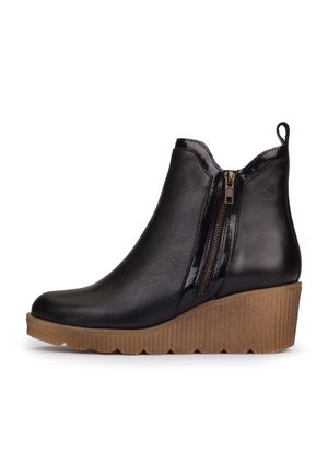Bottine en cuir noir avec fermeture éclair latérale, languette de traction et semelle compensée épaisse marron texturée.