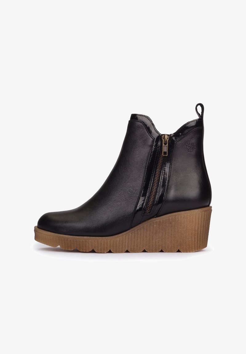 Bottine en cuir noir avec fermeture éclair latérale, languette de traction et semelle compensée épaisse marron texturée.