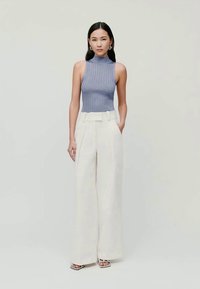 SUADEIRO sem mangas em azul claro, combinado com calças largas em creme de cintura alta, com um cinto na cintura e pregas subtis.
