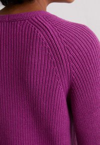 Lila gestrickter Pullover mit gerippter Textur, runder Ausschnitt und detaillierten Schulternähten, der eine enganliegende Passform und leichten Stretch bietet.