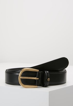 Cinturón de cuero negro con un acabado suave, que presenta una hebilla de metal de color dorado y un diseño elegante. Contiene un pequeño acento de logo cerca de la hebilla.