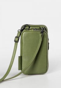 Green leather crossbody bag with zipper closure, adjustable strap, and smooth texture; features contrasting black hardware accents.