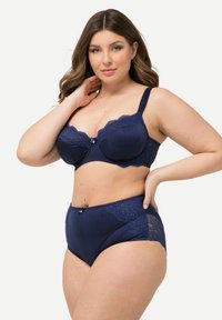 Marineblauwe lingerieset met een balconette beha met kantaccenten en bijpassende high-waisted slip, beide met ribbelstructuur en strikdetail.