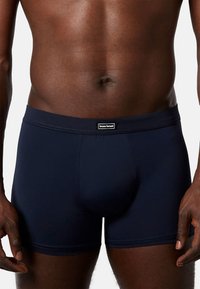 Boxer aderenti blu navy realizzati in tessuto elasticizzato; texture liscia con una vestibilità aderente, caratterizzati da un logo applicato sulla cintura.