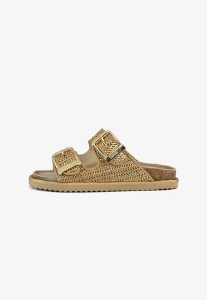 Gouden geweven slidersandalen met twee grote gespen, kurken voetbed en een gestructureerde rubberen zool. Open teen- en hielontwerp voor gemakkelijk aan- en uittrekken.