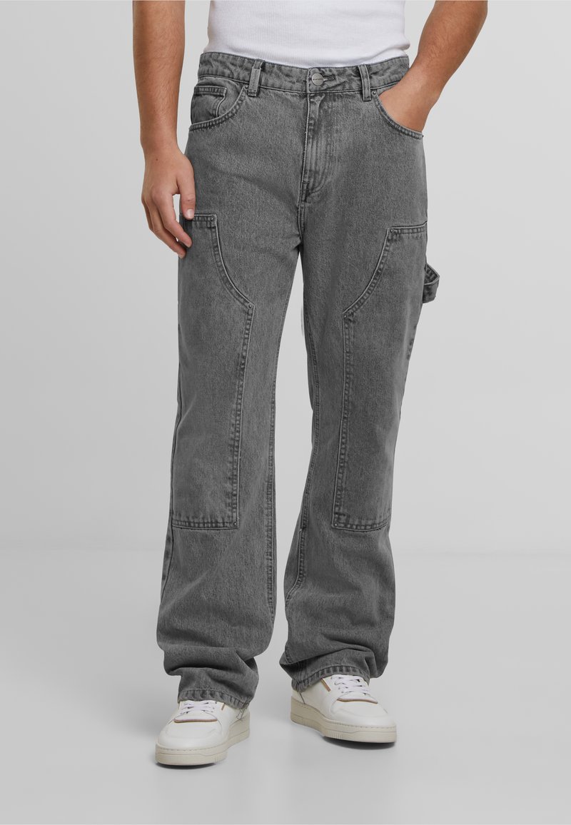 Grå denim cargo bukser med afslappet pasform, fem lommer og syningsdetaljer. Båret med hvide sneakers.