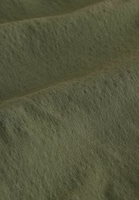 Textúrájú zöld anyag, finom bordázott mintával, lágy, matt felülettel és gazdag, föld színű árnyalattal. Kiválóan alkalmas különböző felhasználásokhoz.