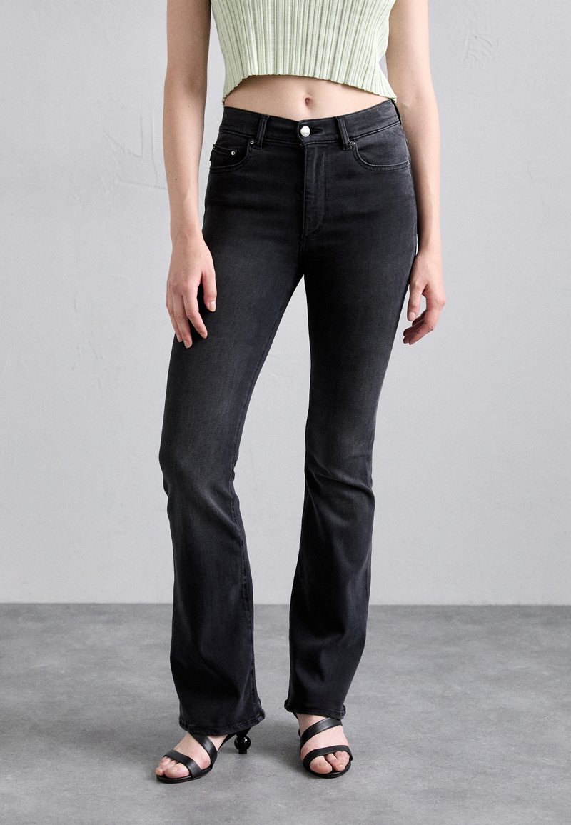 Black flared jeans made from denim, featuring a high waist, front pockets, and a button fastening. The fabric has a smooth texture.