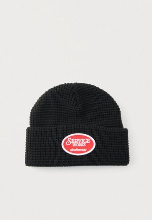 Berretto di maglia nero con motivo a rilievo. Presenta una toppa ovale rossa e bianca con la scritta "SERVICE WORKS chefswear". Design con risvolto.