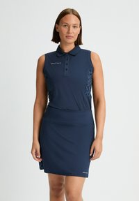 Vestido de polo sin mangas de color azul marino con cuello tipo polo, corsé ajustado y falda amplia. Presenta detalles con estampados en los laterales y un logotipo.
